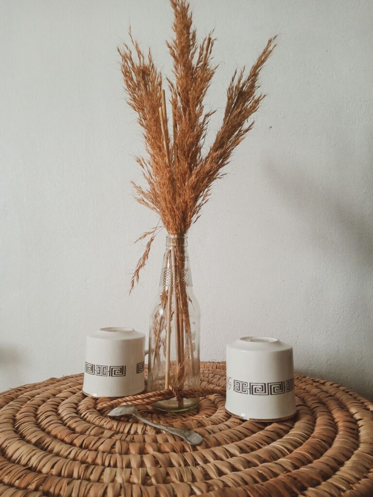 Dried grasses in a vase resting on a handwoven natural mat
